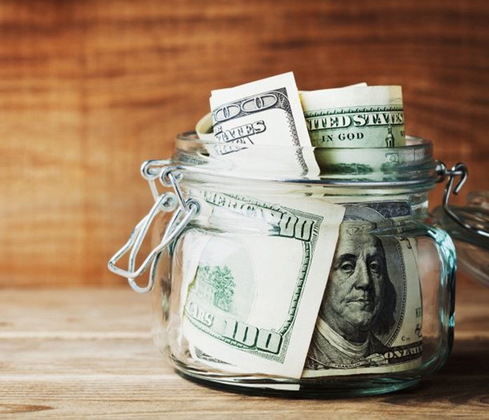 A jar of Benjamins sitting on a wood surface