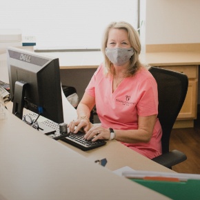 Dental team member sitting at computer behind front desk