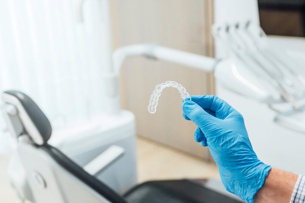 Dentist with blue gloves holding clear aligner